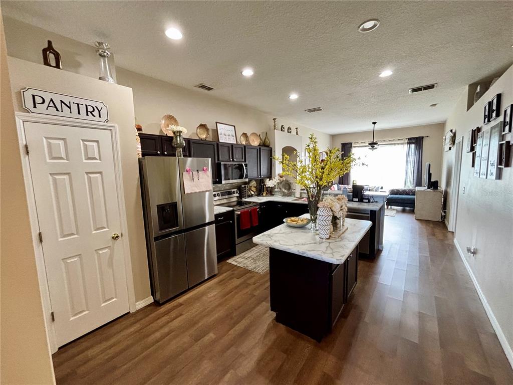 A kitchen with dark cabinets, stainless steel appliances, and a marble-topped island — 2146 BLACKSTONE LANDING DRIVE, KISSIMMEE, FL