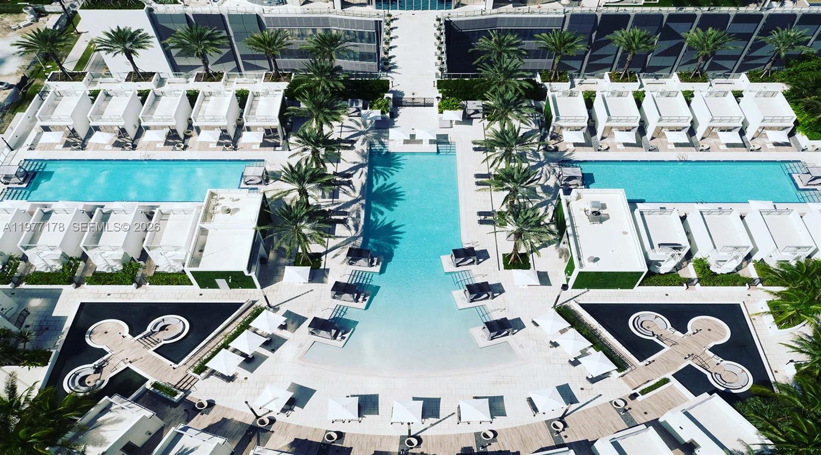 An aerial view shows a luxury resort pool area with cabanas and palm trees — 851 NE 1st Ave # 811, Miami FL 33132, MIAMI, FL