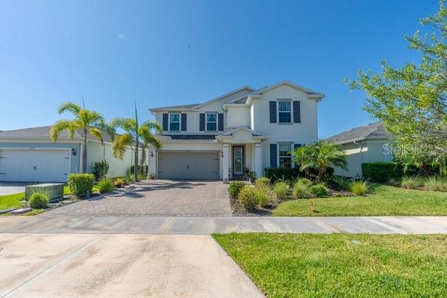 A two-story suburban house with a light-colored exterior, a paved driveway, and palm trees — 42982 PARKSIDE COURT, PUNTA GORDA, FL