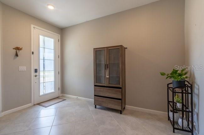 An entryway features light tile flooring, a white front door, and a wooden storage cabinet — 42982 PARKSIDE COURT, PUNTA GORDA, FL