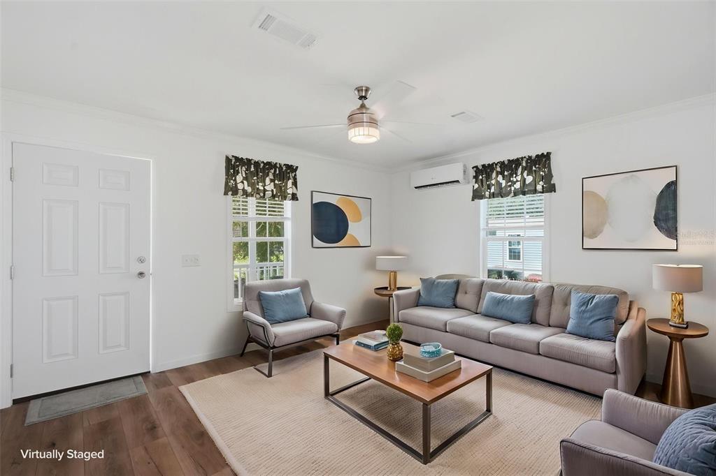 A virtually staged living room features a gray sofa, armchairs, coffee table, and ceiling fan — 4241 E HAWAII LANE, HERNANDO, FL
