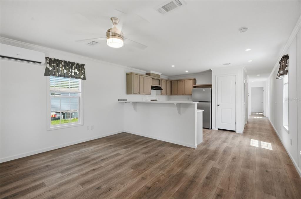An open-concept kitchen and living area features light wood-look flooring, white walls, and cabinetry — 4241 E HAWAII LANE, HERNANDO, FL