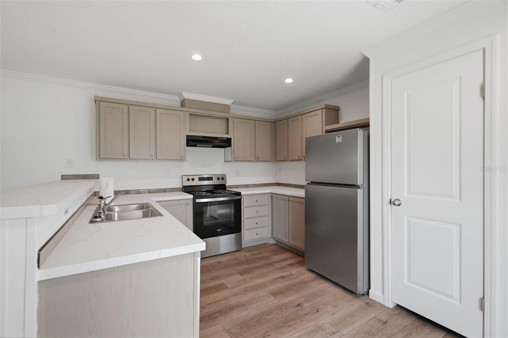 A kitchen features light wood cabinets, stainless steel appliances, and white countertops — 4241 E HAWAII LANE, HERNANDO, FL