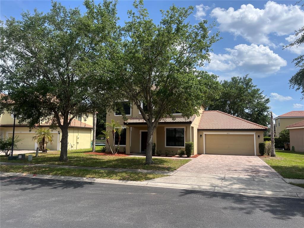 A two-story suburban house with a tan exterior, tiled roof, and a two-car garage — 2821 SCENIC LANE, KISSIMMEE, FL