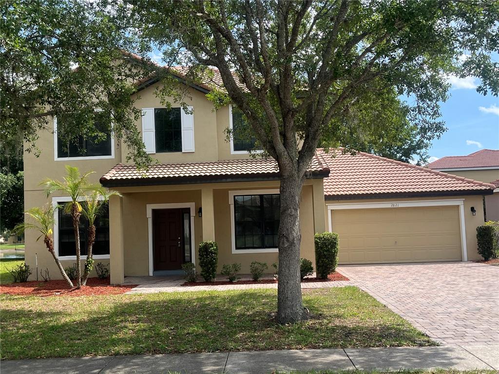 A two-story house with a tan stucco exterior, tile roof, and attached two-car garage — 2821 SCENIC LANE, KISSIMMEE, FL