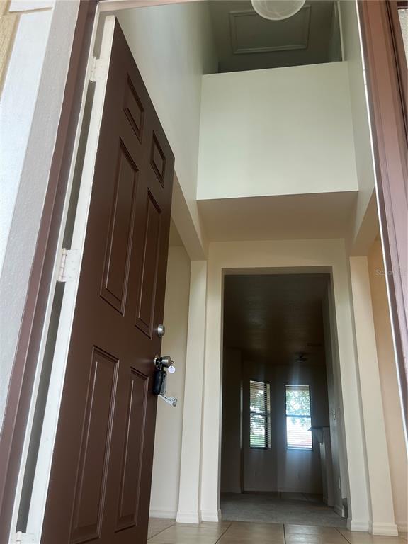 A brown front door opens into a high-ceilinged entryway with tile flooring and interior views — 2821 SCENIC LANE, KISSIMMEE, FL
