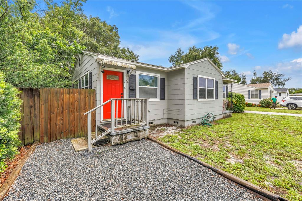 A small, light gray house with a bright red door and a gravel driveway — 416 61ST AVENUE NE, ST PETERSBURG, FL
