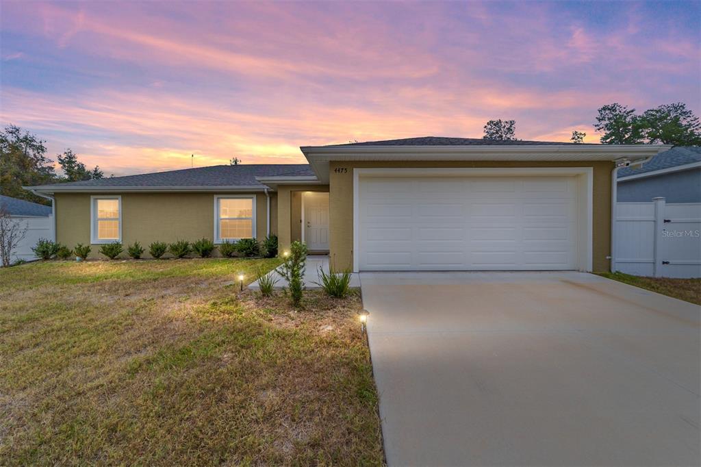 A single-story house with a beige exterior, a two-car garage, and a concrete driveway — 4475 SW 149TH STREET, OCALA, FL
