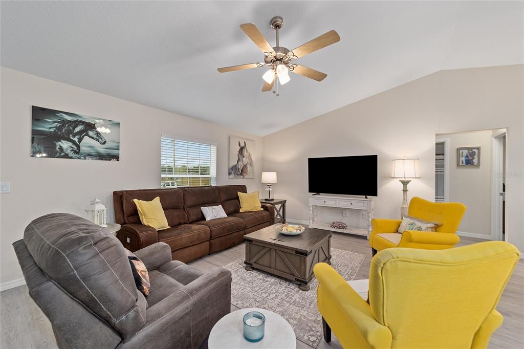 A living room features a brown sofa, two yellow armchairs, and a central coffee table — 4475 SW 149TH STREET, OCALA, FL