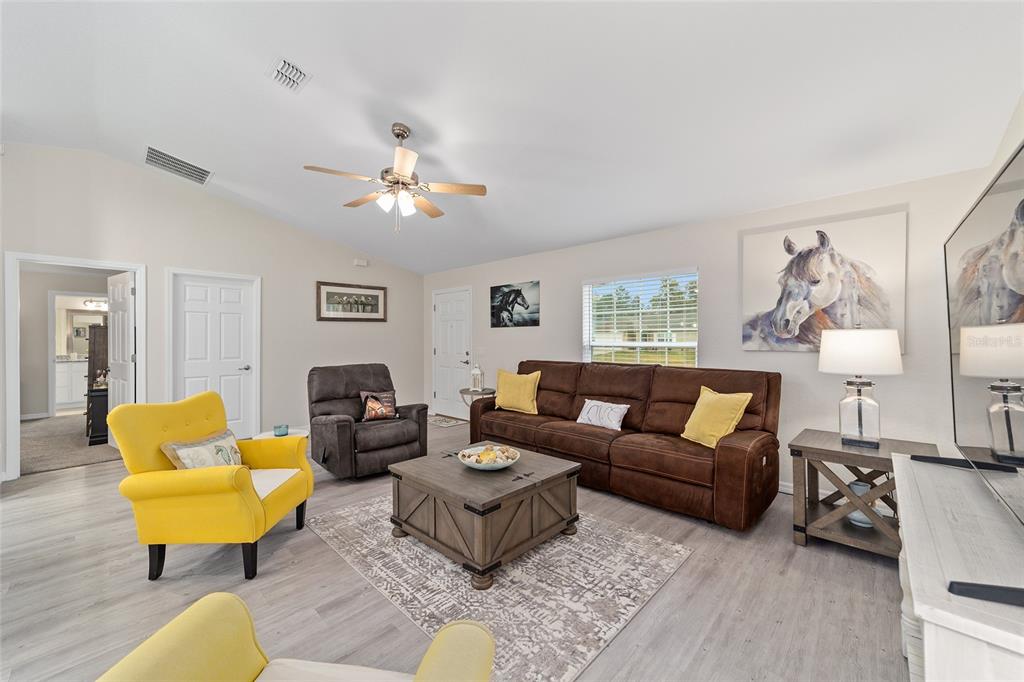 A living room features a brown sofa, yellow armchairs, a coffee table, and horse-themed artwork — 4475 SW 149TH STREET, OCALA, FL
