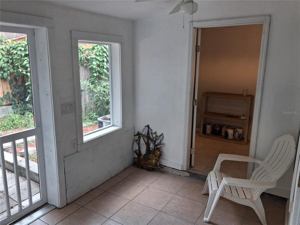 A sunroom with tiled floors, a white plastic chair, and a doorway leading to storage — 1977 SW 69TH DRIVE, GAINESVILLE, FL