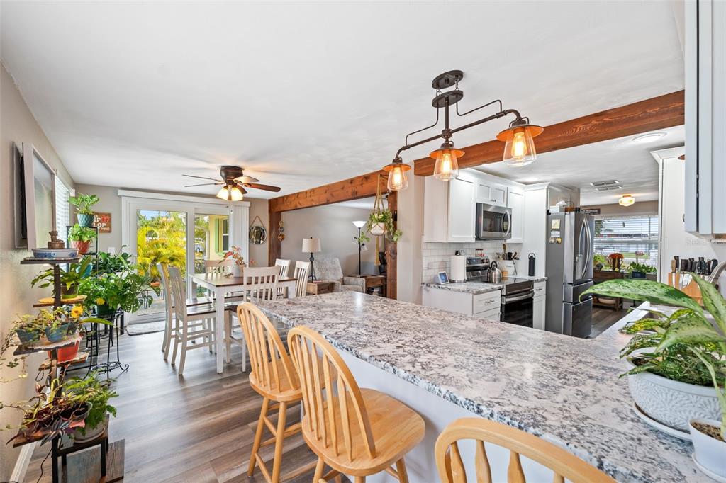 A kitchen with a granite island, wooden bar stools, and an adjacent dining area — 6719 ALBATROSS LANE, HUDSON, FL