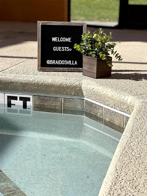 A welcome sign and a small potted plant sit on the edge of a pool — 8947 CANDY PALM RD, KISSIMMEE, FL