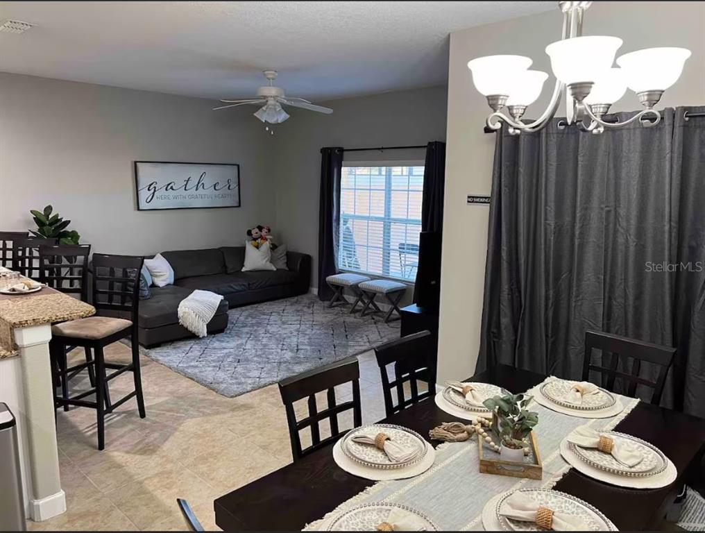 An open-concept living and dining area features tile flooring, a sectional sofa, and dark furniture — 8947 CANDY PALM RD, KISSIMMEE, FL