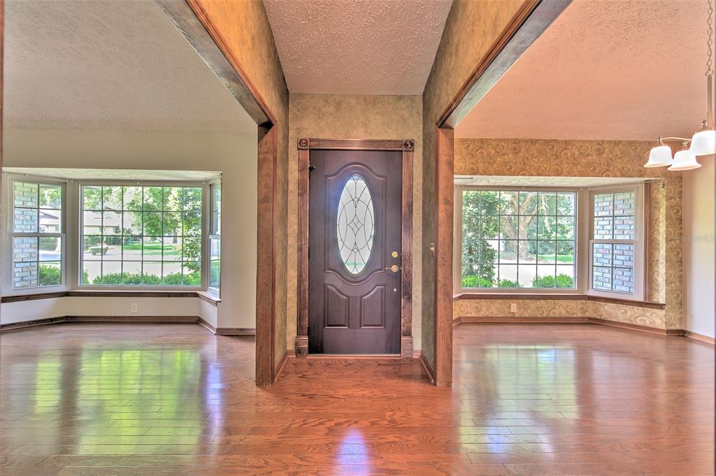An entryway with a dark wood front door, hardwood floors, and two adjacent living areas — 2102 WHITLOCK PLACE, DOVER, FL