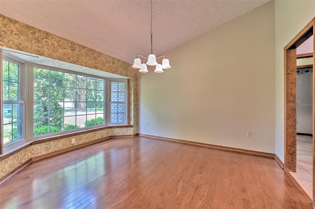 A dining room with hardwood floors, a bay window, wallpaper, and a hanging light fixture — 2102 WHITLOCK PLACE, DOVER, FL