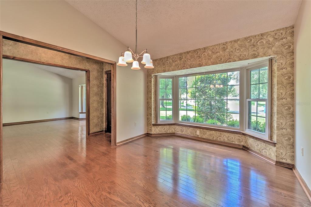 A dining room with hardwood floors, a bay window, and patterned wallpaper — 2102 WHITLOCK PLACE, DOVER, FL