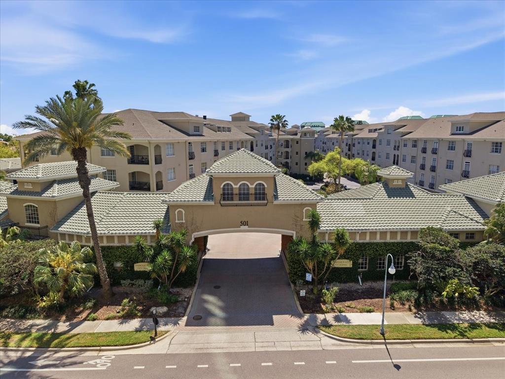 An aerial view of a multi-story apartment complex with a gated entrance and palm trees — 501 KNIGHTS RUN AVENUE UNIT 1320, TAMPA, FL