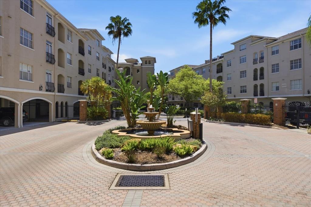 A courtyard features a central tiered fountain surrounded by landscaping between two multi-story apartment buildings — 501 KNIGHTS RUN AVENUE UNIT 1320, TAMPA, FL
