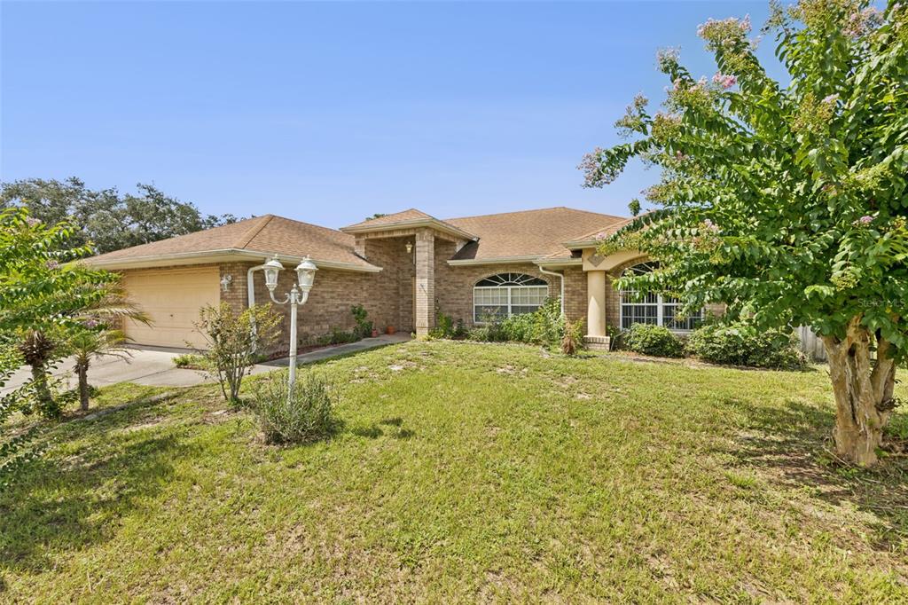 A single-story brick house with a two-car garage and a front yard with trees — 2270 CARSON LANE, DELTONA, FL