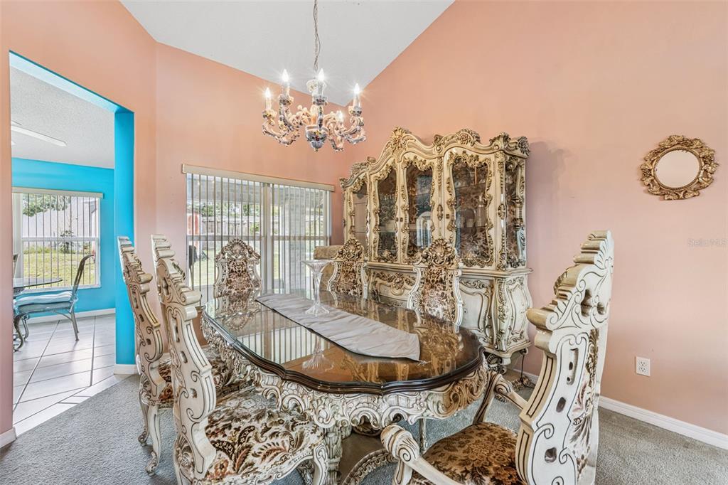 A formal dining room features an ornate table and chairs set beneath a crystal chandelier — 2270 CARSON LANE, DELTONA, FL
