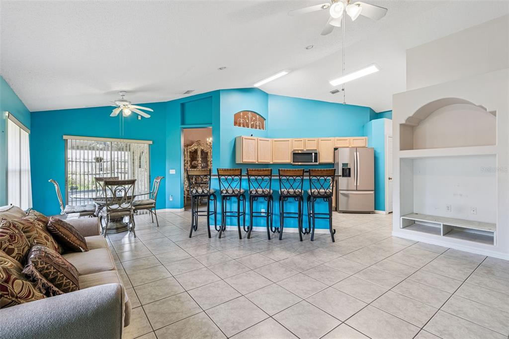 An open-concept living and dining area features bright blue walls, tile flooring, and bar seating — 2270 CARSON LANE, DELTONA, FL