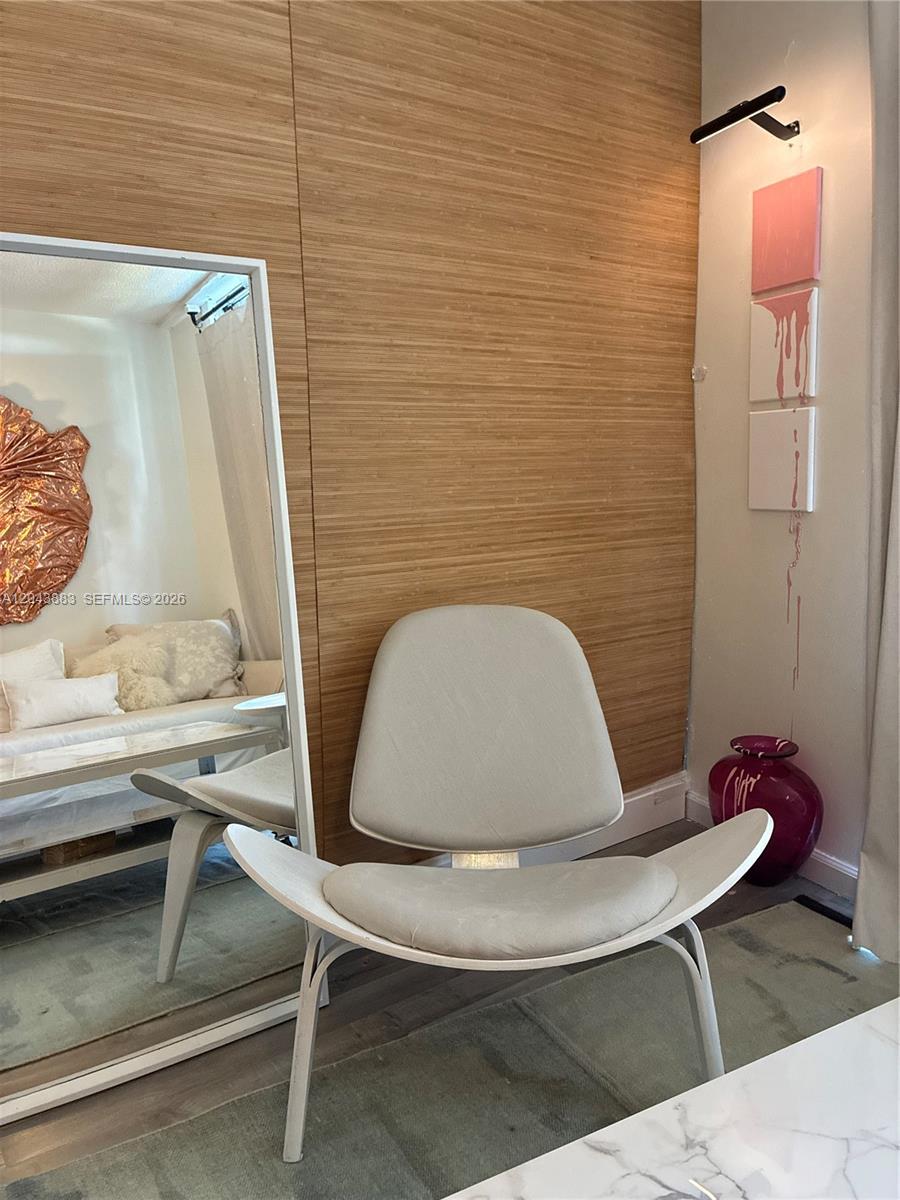 A modern chair sits in front of a wood-paneled wall next to a floor mirror — 900 Bay Dr # 207, Miami Beach FL 33141, MIAMI BEACH, FL