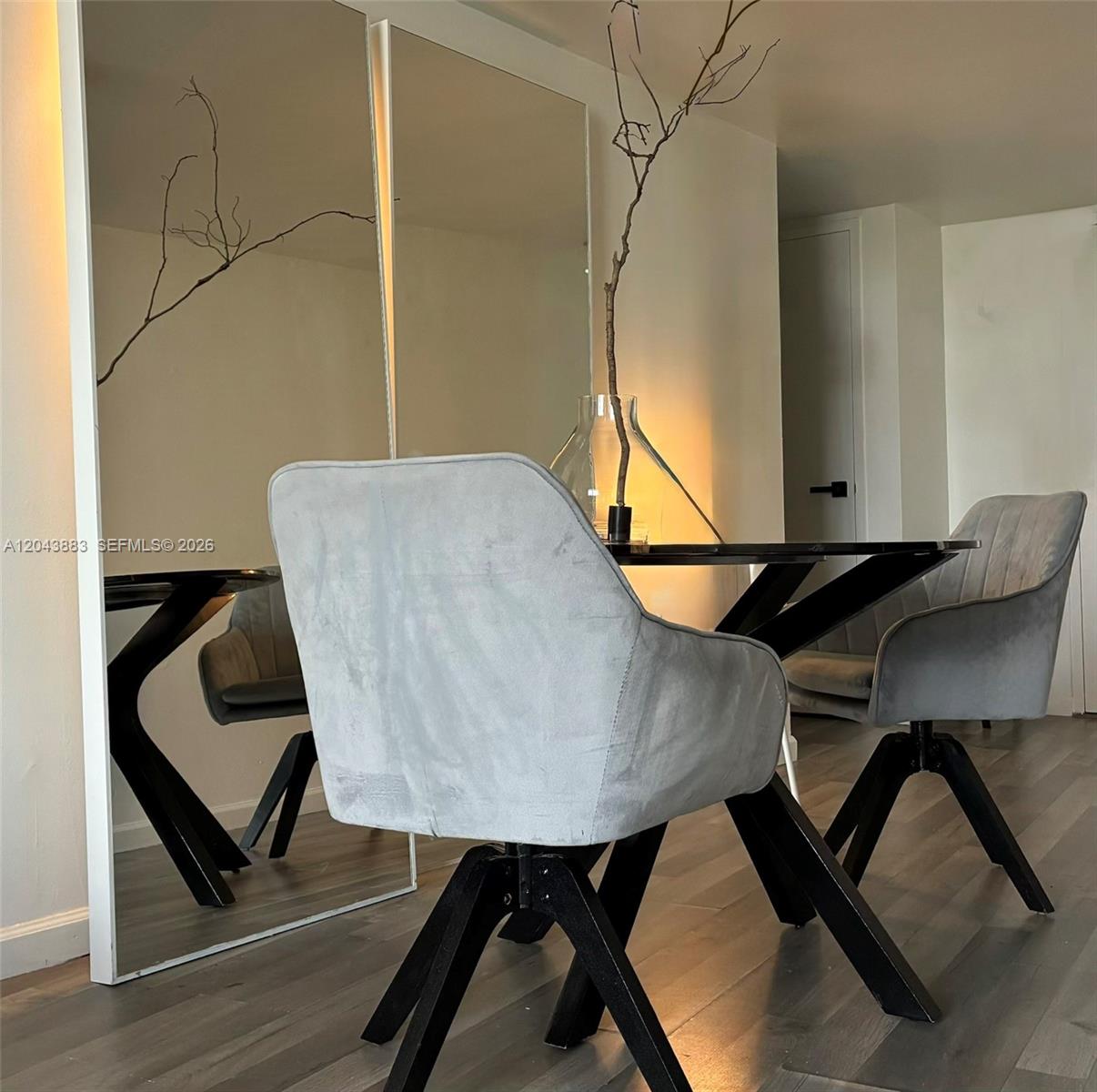 A dining area features two gray velvet swivel chairs at a black table with mirrors — 900 Bay Dr # 207, Miami Beach FL 33141, MIAMI BEACH, FL