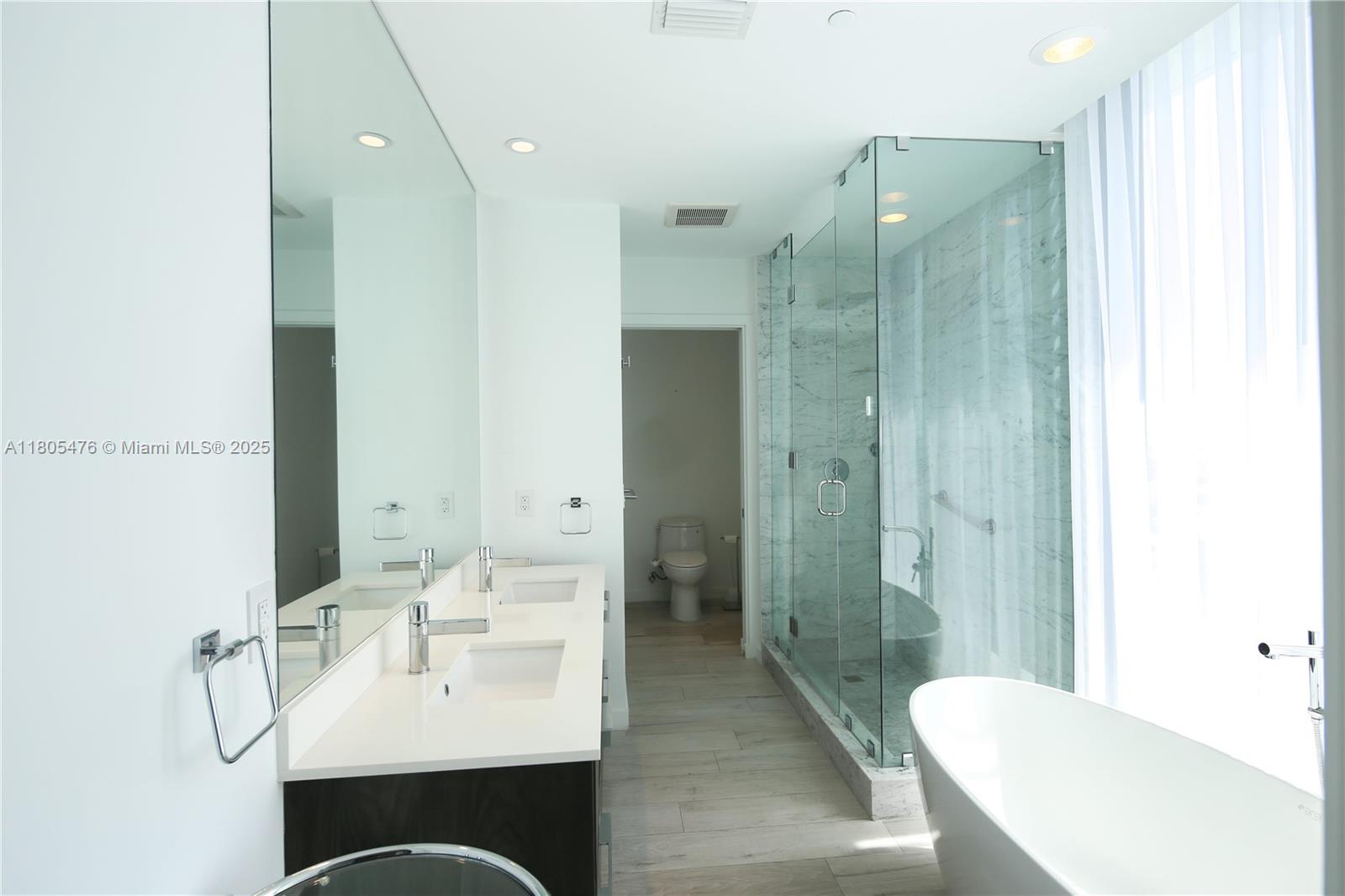A modern bathroom features a double vanity, a glass-enclosed shower, and a freestanding soaking tub — 480 NE 31 St # 2607, Miami FL 33137, MIAMI, FL