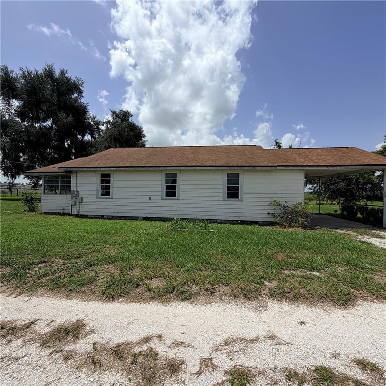 A single-story house with white horizontal siding, a brown roof, and an attached carport — 15016 SCANT STREET, WIMAUMA, FL