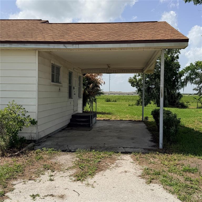 A side view of a house exterior featuring a covered concrete carport and stairs — 15016 SCANT STREET, WIMAUMA, FL