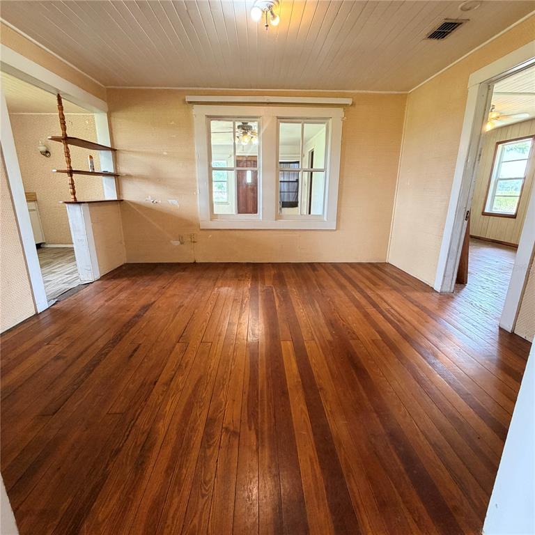 An empty room with hardwood floors, a central window, and a wooden shelving unit — 15016 SCANT STREET, WIMAUMA, FL