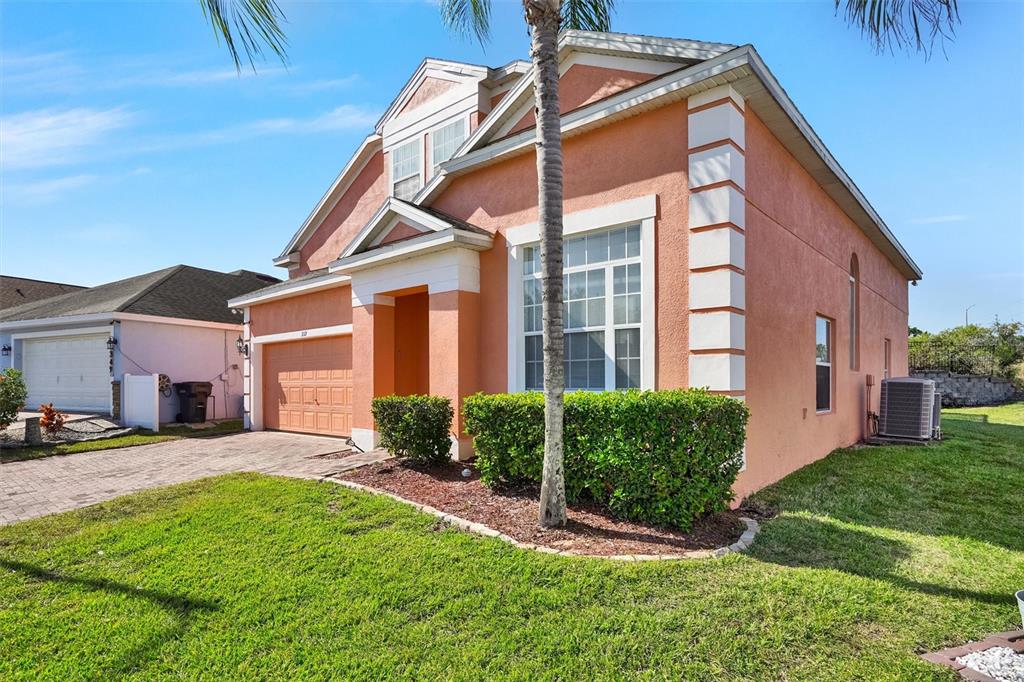 A two-story peach-colored house with a paved driveway, a palm tree, and green landscaping — 359 VIZCAY WAY, DAVENPORT, FL