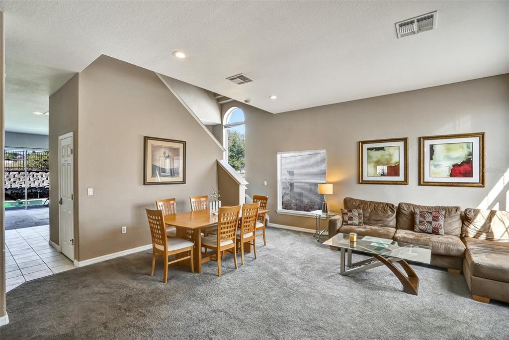 A living and dining area features gray carpeting, tan walls, a sectional sofa, and a table — 359 VIZCAY WAY, DAVENPORT, FL