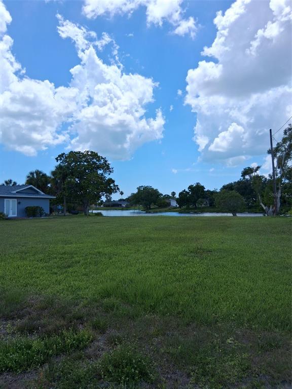 A grassy vacant lot overlooks a small lake under a bright blue sky — 6614 SABINA ROAD, SARASOTA, FL