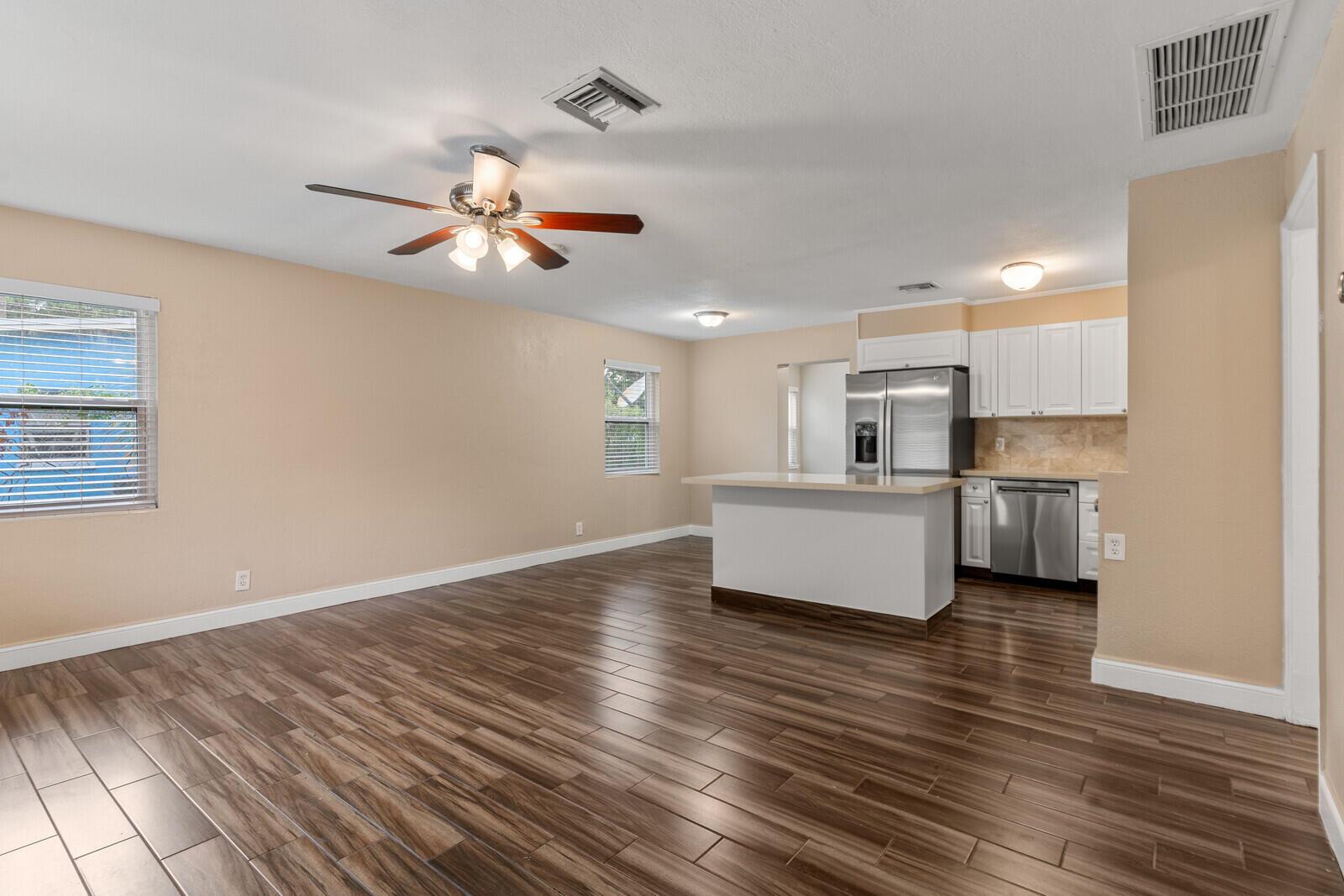 An open-concept living area with wood-look tile floors, a ceiling fan, and a kitchen island — 957 30th Street, West Palm Beach FL 33407, WEST PALM BEACH, FL