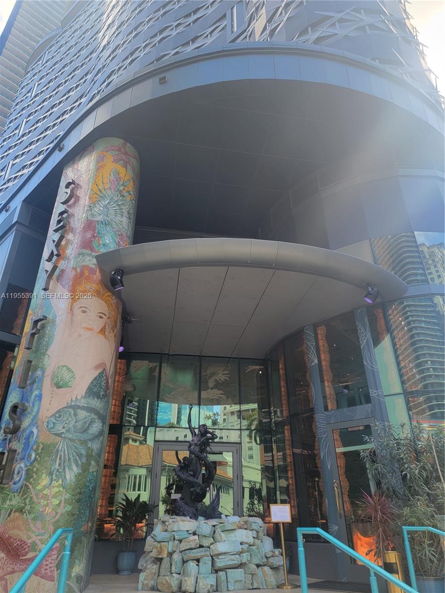 The exterior entrance of a building features a mosaic-covered pillar and a central fountain sculpture — 999 SW 1st Ave # 2302, Miami FL 33130, MIAMI, FL