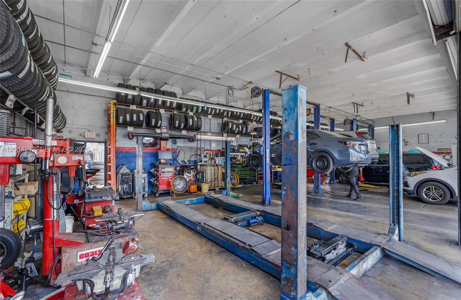 An automotive repair shop features multiple vehicle lifts, tire storage racks, and various mechanical equipment — 8765 Bird Rd, Miami FL 33165, MIAMI, FL