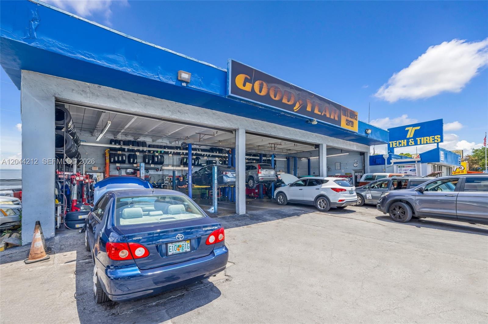 A blue Goodyear auto service center building with multiple open garage bays and parked cars — 8765 Bird Rd, Miami FL 33165, MIAMI, FL