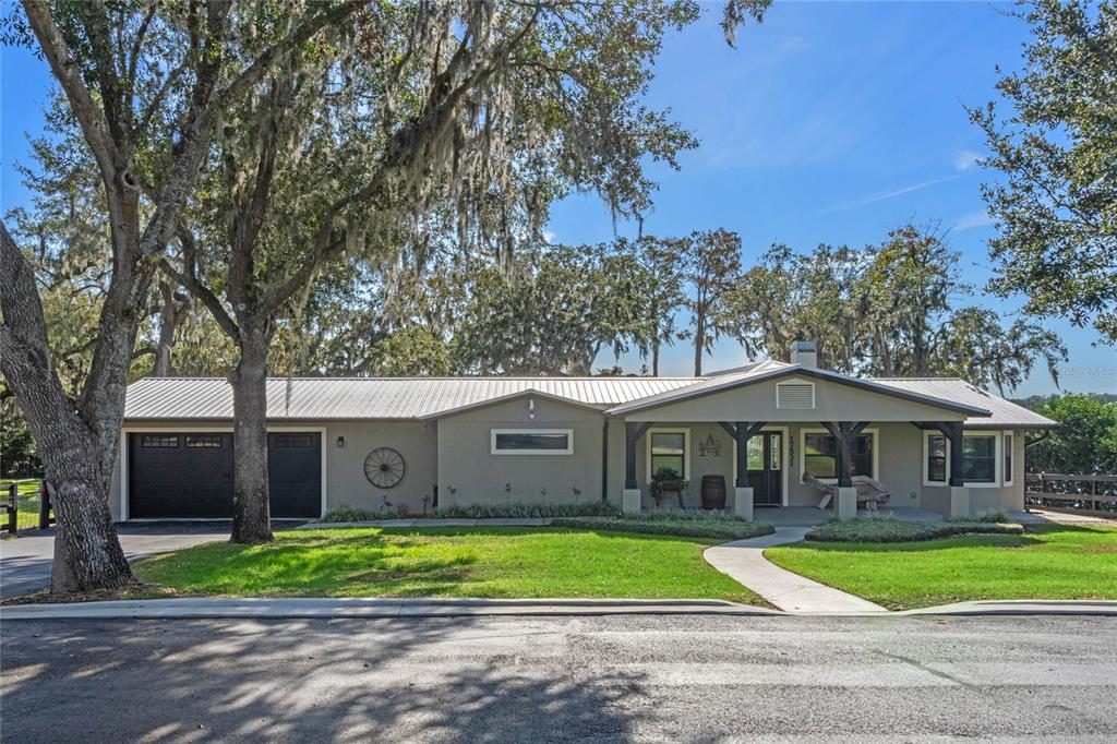 A single-story house with a metal roof, dark garage doors, and a covered front porch — 17531 COUNTY ROAD 455, MONTVERDE, FL