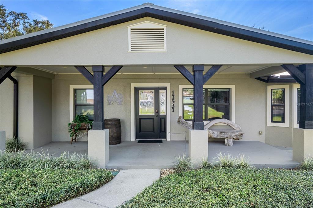 The front exterior of a house features a covered porch with dark wooden support beams — 17531 COUNTY ROAD 455, MONTVERDE, FL