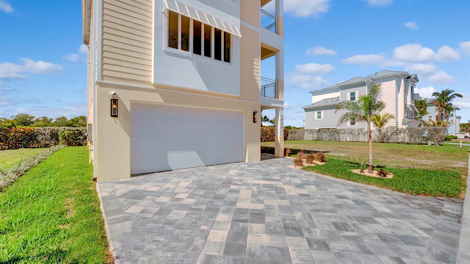 A paved driveway leads to a white garage door on the side of a house — 4857 Watersong Way, Fort Pierce FL 34949, FORT PIERCE, FL