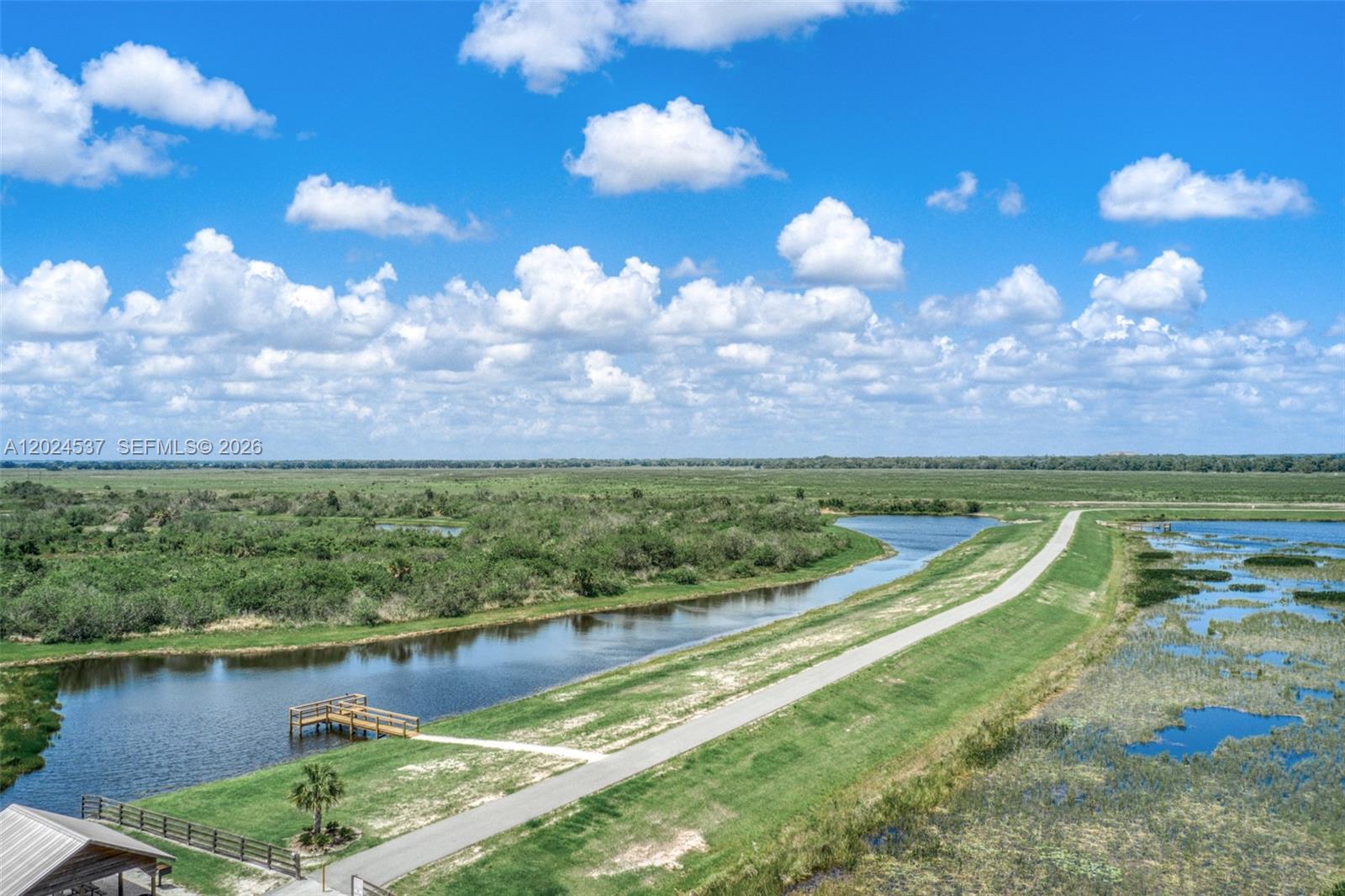An aerial view shows a paved path, a wooden dock, and a canal beside wetlands — 1613 Duane Palmer, Sebring FL 33876, SEBRING, FL