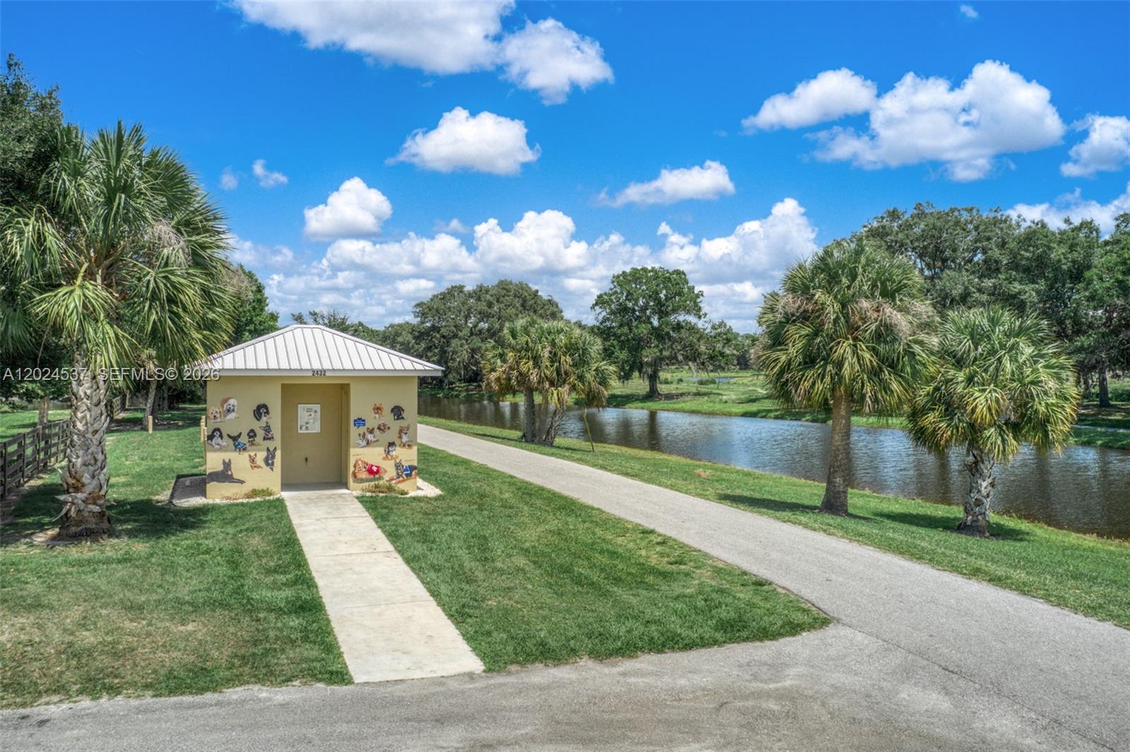 A small, dog-themed building stands beside a paved path and a canal under blue skies — 1613 Duane Palmer, Sebring FL 33876, SEBRING, FL