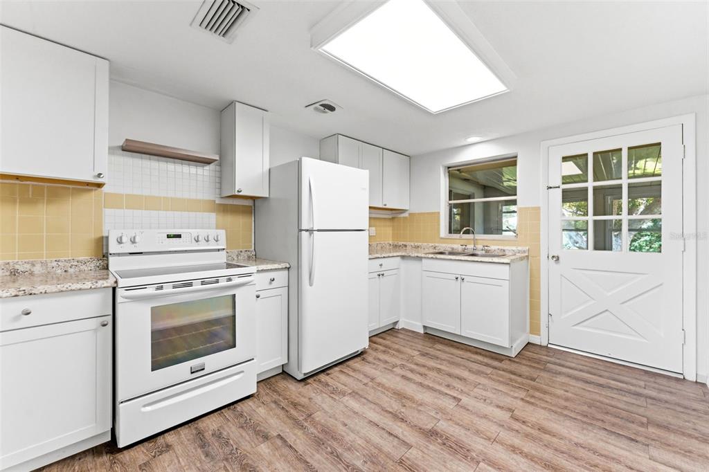 A kitchen with white cabinets, a white stove, a white refrigerator, and yellow tiled walls — 7814 TALISMAN DRIVE, PORT RICHEY, FL