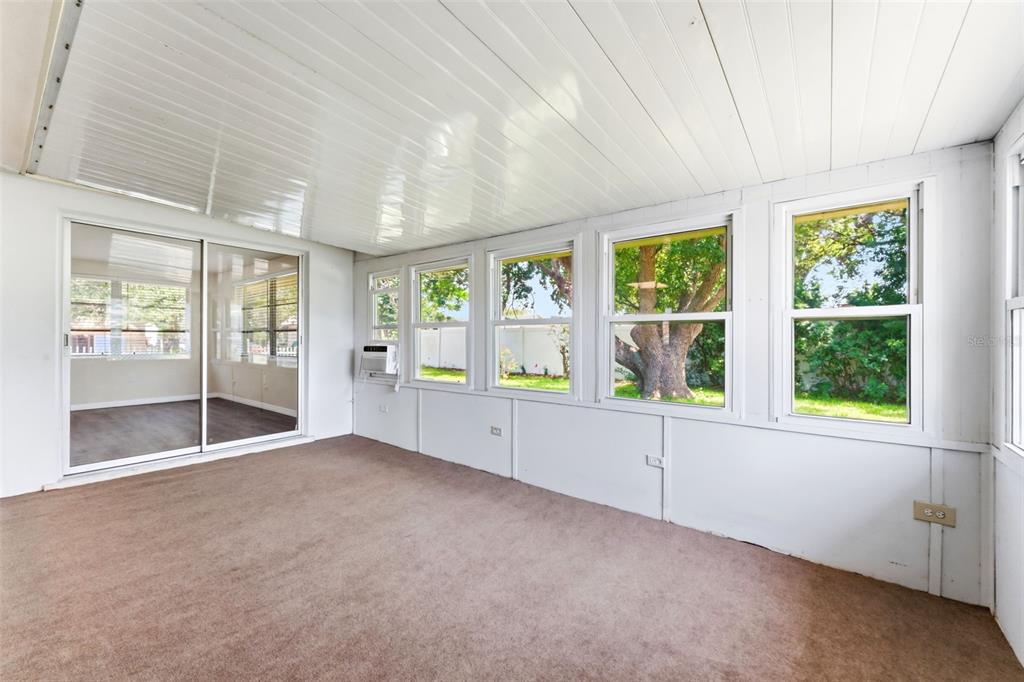 A sunroom features brown carpeting, white paneled walls, a sloped ceiling, and multiple windows — 7814 TALISMAN DRIVE, PORT RICHEY, FL
