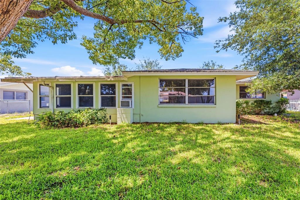 A light green, single-story house with a flat roof and multiple windows sits on grass — 7814 TALISMAN DRIVE, PORT RICHEY, FL