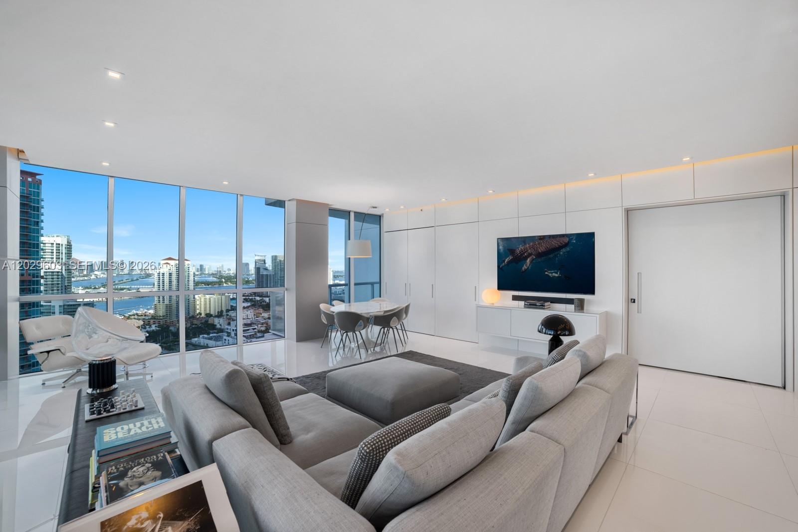 A modern living room features a grey sectional sofa, white tile floors, and floor-to-ceiling windows — 50 S Pointe Dr # 2903, Miami Beach FL 33139, MIAMI BEACH, FL