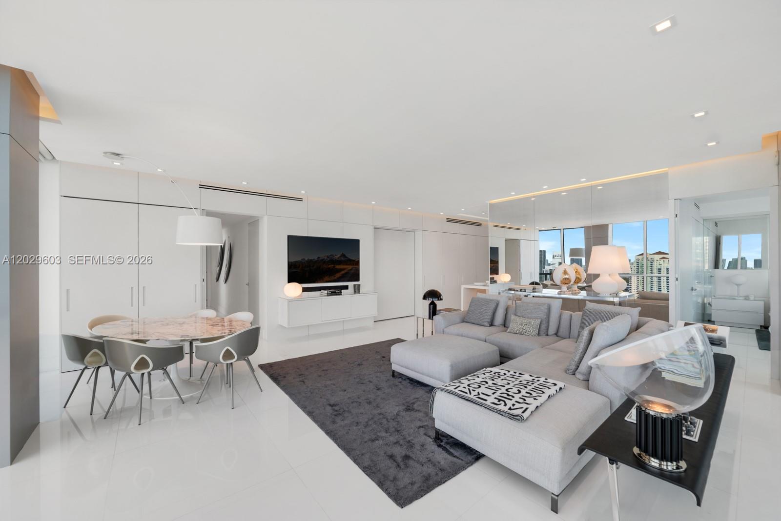 A modern living room features a grey sectional sofa, dining area, and white tiled floors — 50 S Pointe Dr # 2903, Miami Beach FL 33139, MIAMI BEACH, FL