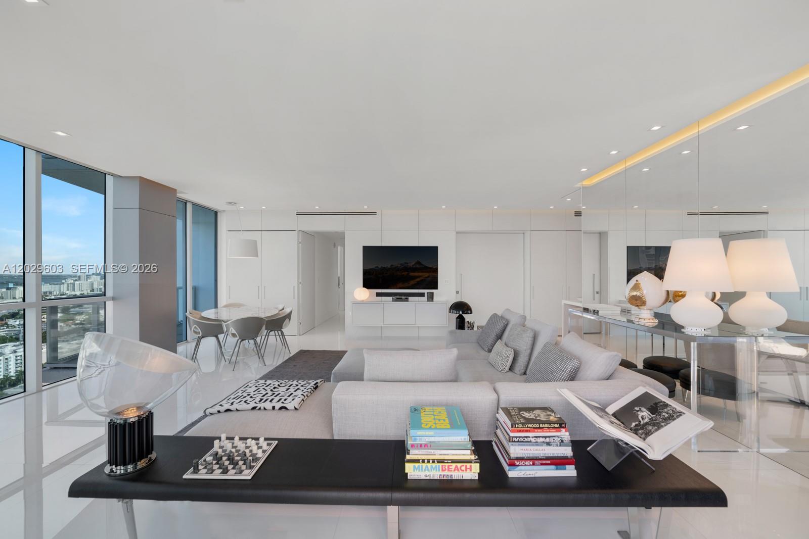 A modern, white-toned living room features a sectional sofa, a dining area, and floor-to-ceiling windows — 50 S Pointe Dr # 2903, Miami Beach FL 33139, MIAMI BEACH, FL
